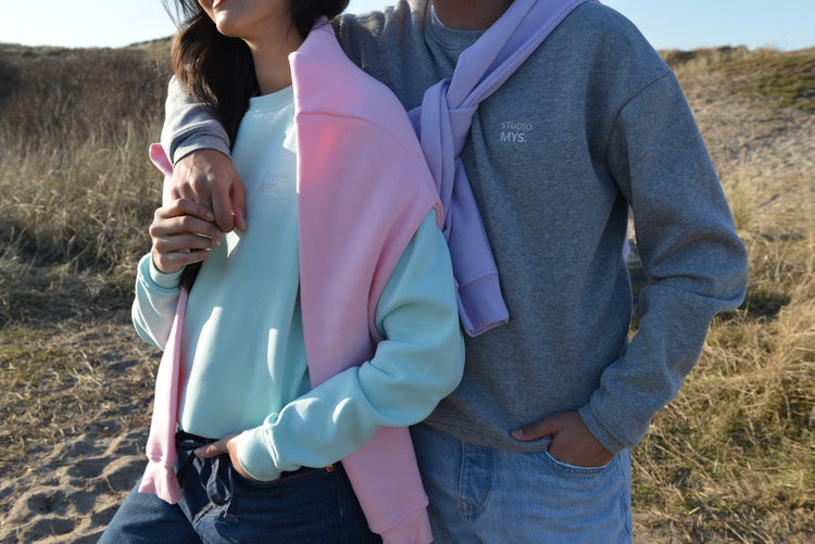 A couple in relaxed fit sweaters, highlighting sustainable style and comfort in a natural setting.